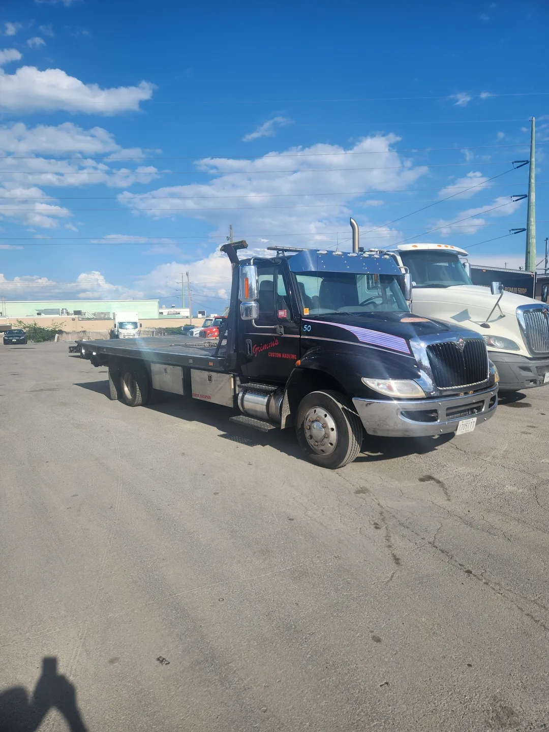 A tow truck parked in the parking lot of a large building.